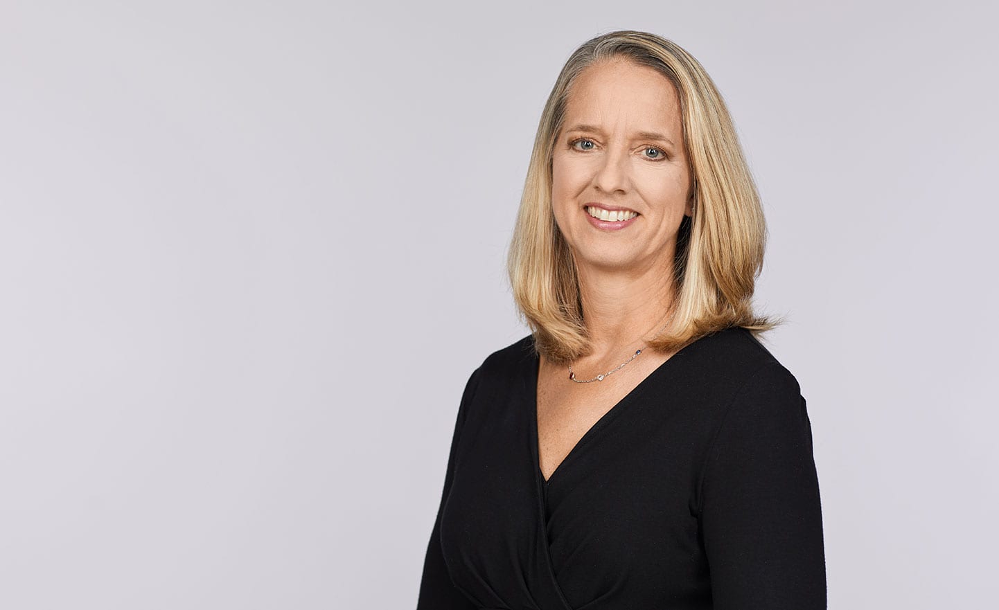 Star Stefka Borg in a black V-neck stands against a light gray background.