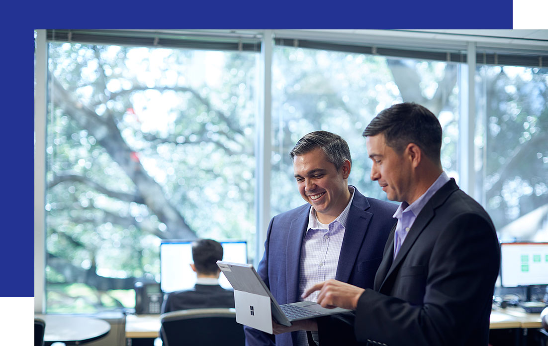 Access-Sciences-Business-Strategy-Frquently-Asked-Questions Two businessmen discuss Business Strategy Services over a laptop in a modern office.