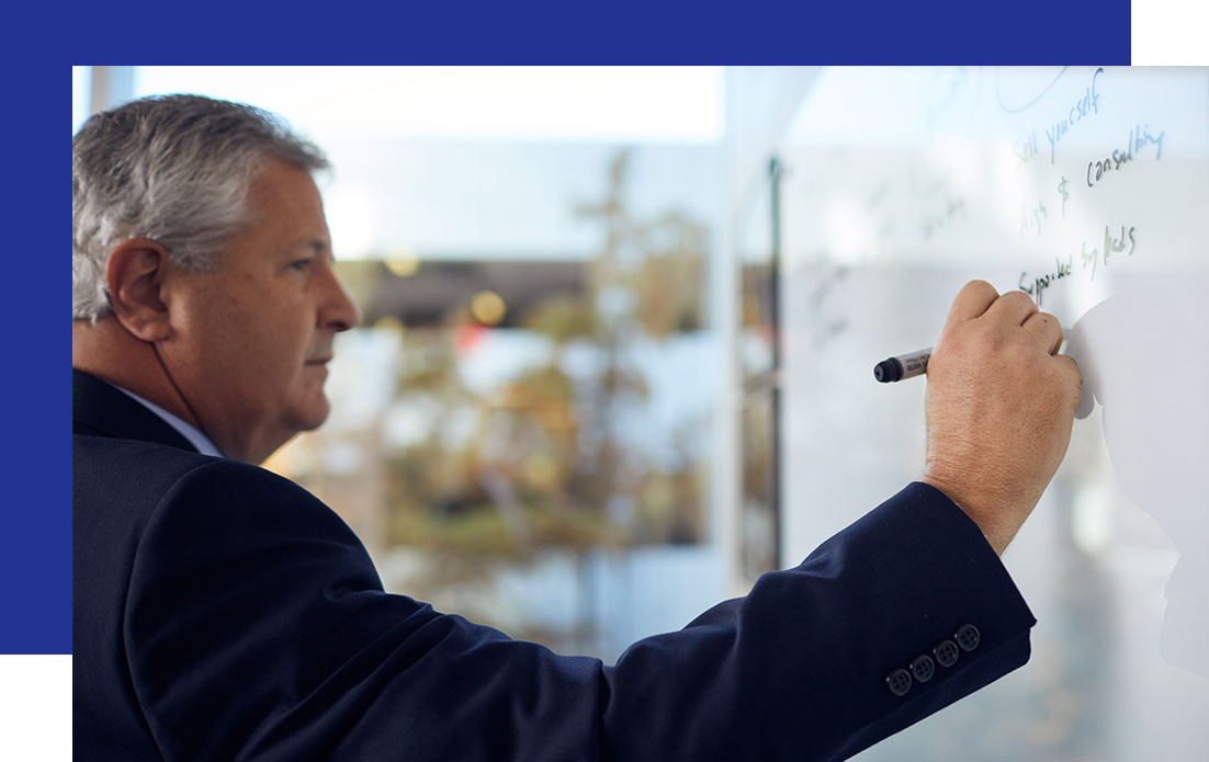 Access-Sciences-Content-Analysis-and-Classification-Frequently-Asked-Questions A suited man writes notes on a whiteboard, focused on content analysis, with a blurred background.