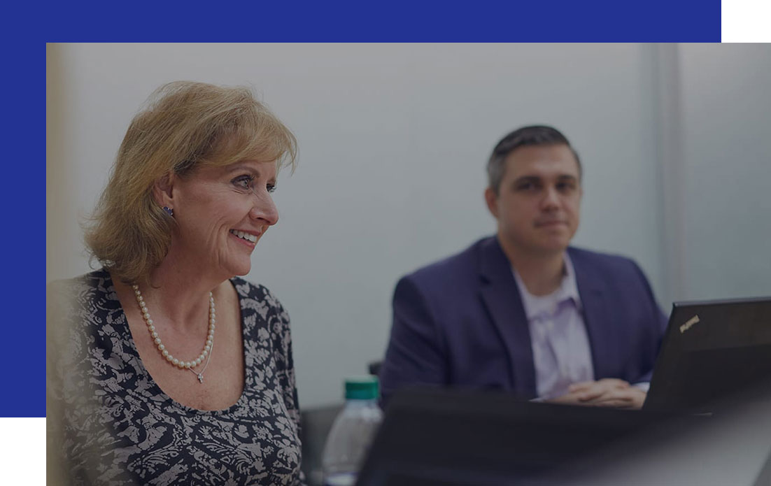 Access-Sciences-Records-Management-Frequently-Asked-Questions A woman and a suited man sit at a table with laptops, focused on records management.