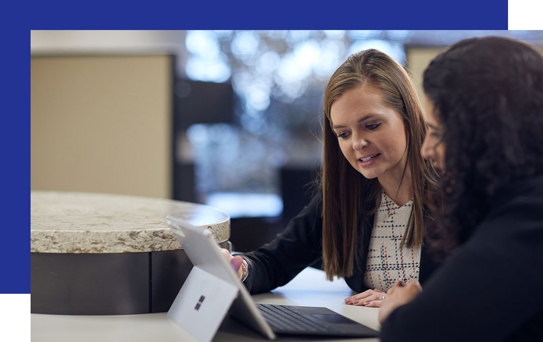 Access-Sciences-Regulatory-and-Audit-Compliance-FAQ Two women sit at a table, discussing information regulations and audits while looking at a laptop screen.