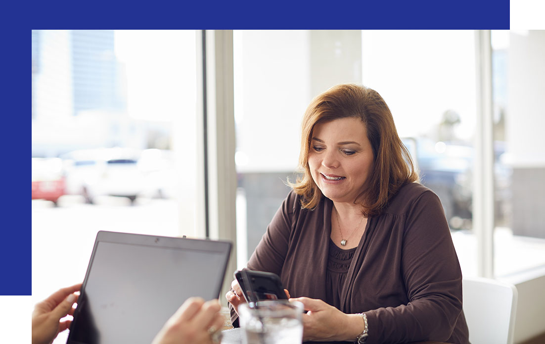 Access-Sciences-Technology-Procurement-Frequently-Asked-Questions A woman smiles at her smartphone, discussing technology procurement.