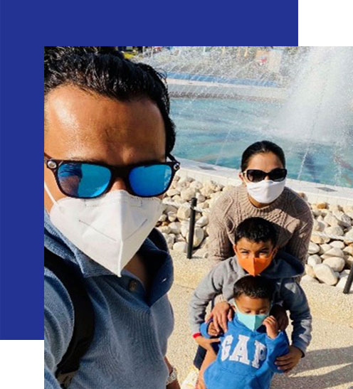 Access-Sciences-Blog-Supporting-Working-Moms-SAPANA-RAUT A masked family of four poses for a selfie near a fountain.