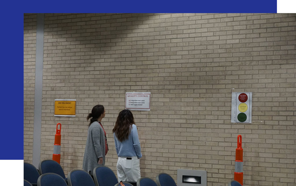 Access-Sciences-in-Baton-Rouge2 Two people read signs by a beige brick wall, with orange cones and blue chairs nearby, at Louisiana’s DEQ office.