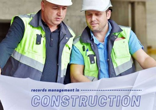 Two construction workers wearing safety vests and hard hats look at a large blueprint. The text on the blueprint reads, records management in CONSTRUCTION—a crucial practice for E&C Companies.